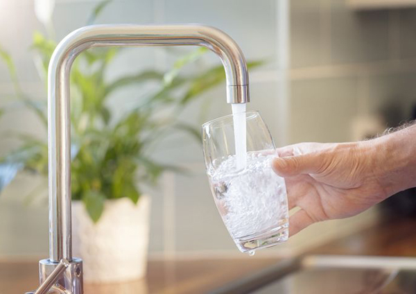 A person filling a glass with water from a tap